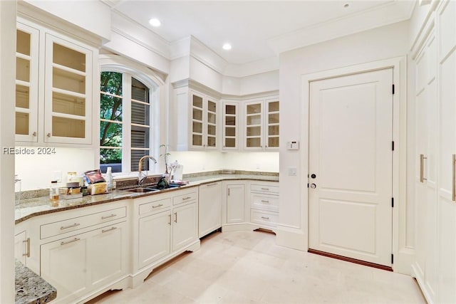 kitchen with sink, light stone counters, ornamental molding, white dishwasher, and white cabinets