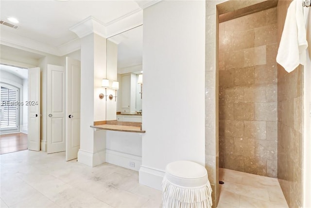 bathroom with crown molding, tiled shower, and vanity