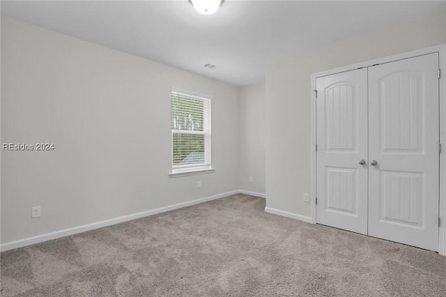 unfurnished bedroom featuring light carpet and a closet