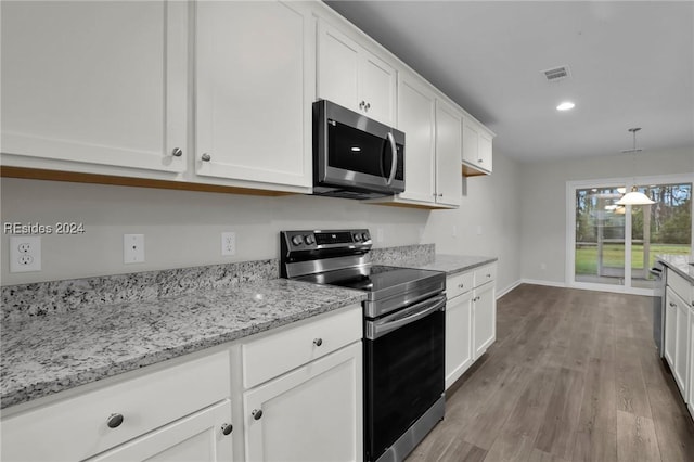 kitchen featuring hanging light fixtures, appliances with stainless steel finishes, white cabinets, and light wood-type flooring