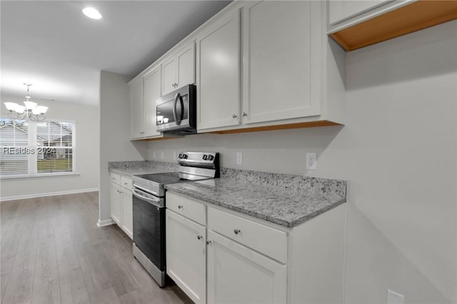 kitchen featuring an inviting chandelier, decorative light fixtures, stainless steel appliances, light stone countertops, and white cabinets