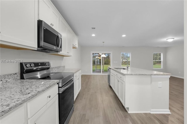 kitchen featuring white cabinetry, sink, stainless steel appliances, and an island with sink