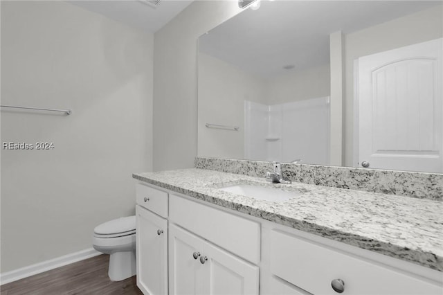 bathroom with vanity, wood-type flooring, a shower, and toilet