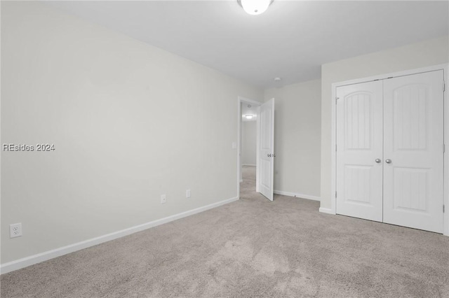 unfurnished bedroom featuring light colored carpet and a closet