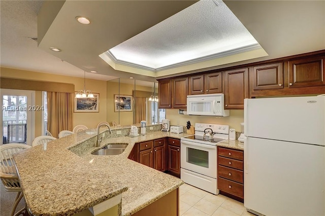 kitchen featuring white appliances, a tray ceiling, a kitchen breakfast bar, and sink