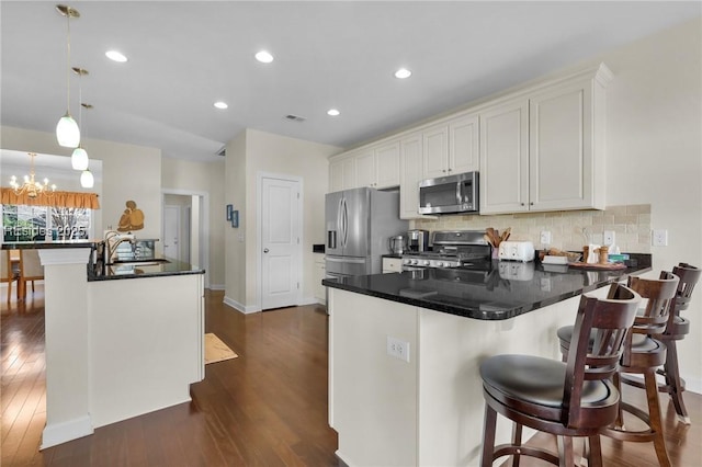 kitchen featuring sink, stainless steel appliances, tasteful backsplash, decorative light fixtures, and kitchen peninsula