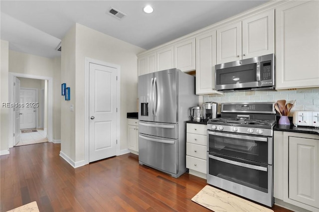 kitchen featuring stainless steel appliances, dark wood-type flooring, white cabinets, and backsplash