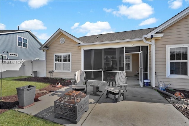 rear view of house featuring a patio, a sunroom, a yard, and an outdoor fire pit