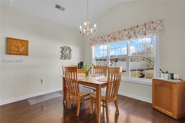 dining space featuring dark hardwood / wood-style flooring, lofted ceiling, and an inviting chandelier