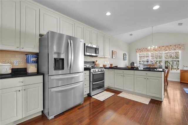 kitchen with vaulted ceiling, appliances with stainless steel finishes, and white cabinets