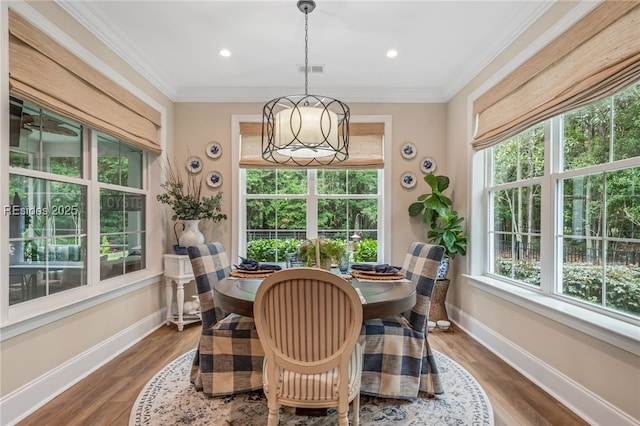 dining space with crown molding, hardwood / wood-style floors, and an inviting chandelier