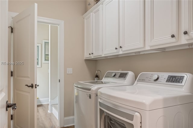 laundry area featuring washing machine and dryer, cabinets, and light wood-type flooring