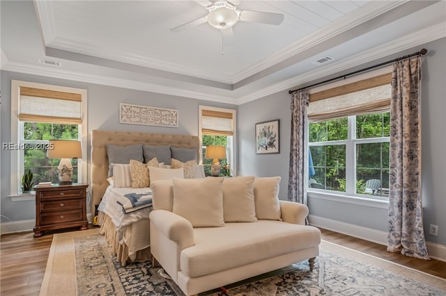 bedroom with light hardwood / wood-style flooring, a raised ceiling, and ceiling fan