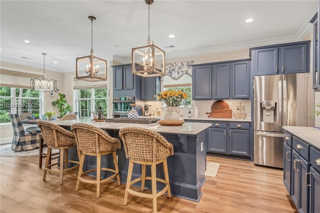 kitchen with pendant lighting, crown molding, appliances with stainless steel finishes, a kitchen island, and light wood-type flooring