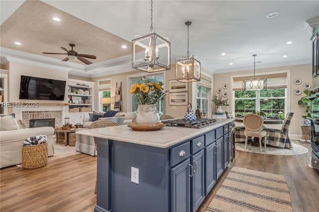 kitchen with a kitchen island, blue cabinets, hanging light fixtures, built in shelves, and light hardwood / wood-style flooring