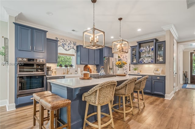 kitchen featuring backsplash, a kitchen island, stainless steel appliances, blue cabinets, and light wood-type flooring