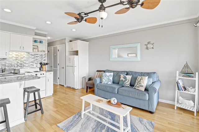 living room featuring ornamental molding, light hardwood / wood-style floors, and ceiling fan