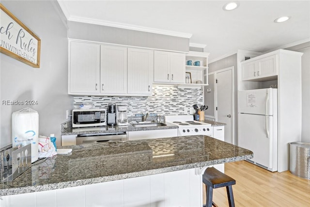 kitchen with white fridge, white cabinets, and dark stone counters