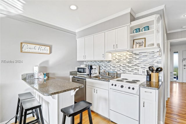 kitchen featuring electric stove, white cabinetry, dark stone countertops, a kitchen breakfast bar, and kitchen peninsula