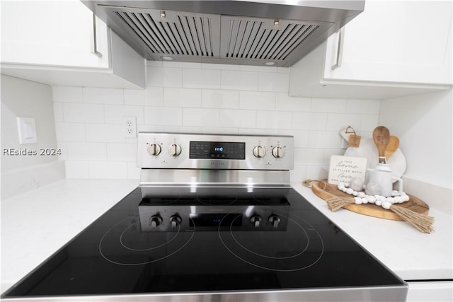 kitchen featuring wall chimney exhaust hood, white cabinetry, stainless steel electric range oven, and tasteful backsplash