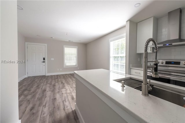 kitchen with light hardwood / wood-style flooring and wall chimney exhaust hood