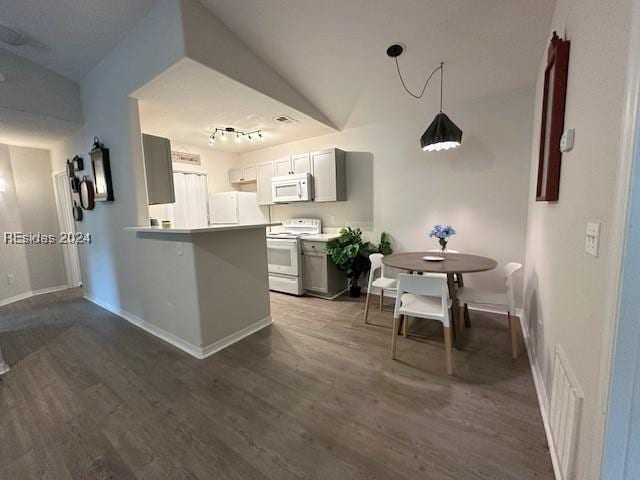 kitchen with vaulted ceiling, dark hardwood / wood-style flooring, kitchen peninsula, track lighting, and white appliances