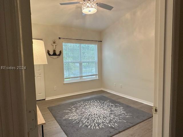 unfurnished room featuring dark hardwood / wood-style flooring, vaulted ceiling, and ceiling fan