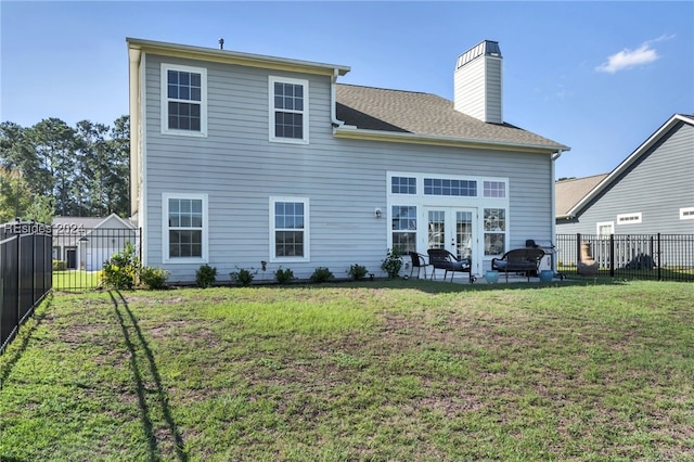 rear view of property with a patio, a fire pit, a lawn, and french doors