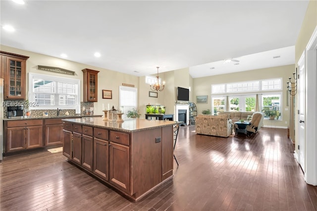 kitchen featuring pendant lighting, decorative backsplash, dark stone counters, a center island, and dark wood-type flooring