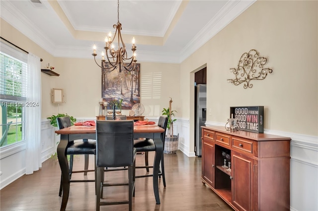 dining space with ornamental molding, dark hardwood / wood-style floors, a chandelier, and a tray ceiling