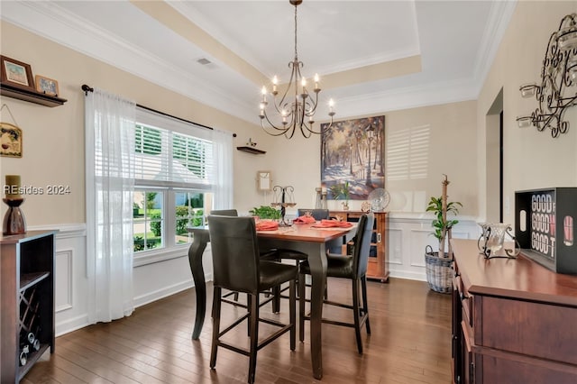 dining room featuring crown molding, dark wood-type flooring, a raised ceiling, and a chandelier