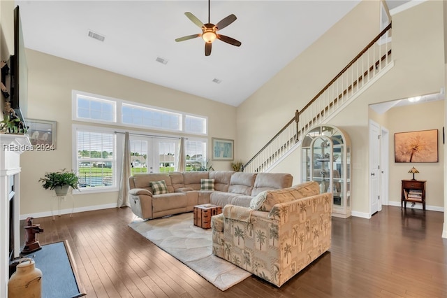 living room with ceiling fan, a towering ceiling, dark hardwood / wood-style flooring, and french doors