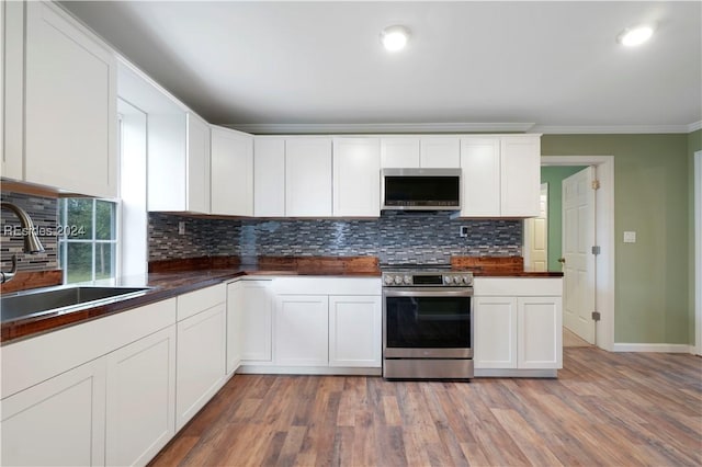 kitchen featuring appliances with stainless steel finishes, hardwood / wood-style floors, sink, white cabinets, and crown molding