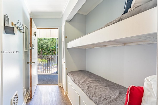 bedroom with multiple windows, crown molding, wood-type flooring, and access to exterior