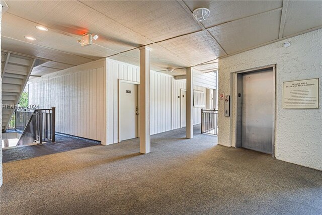 empty room with elevator and dark carpet