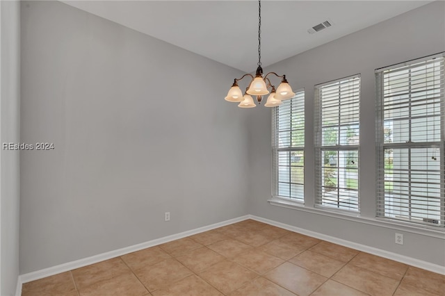 tiled spare room with a chandelier