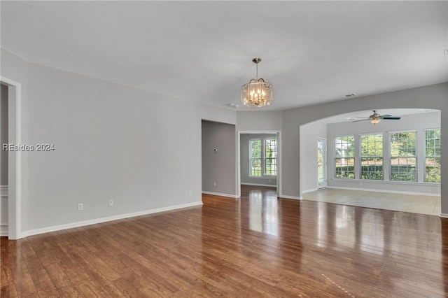 spare room featuring hardwood / wood-style floors and ceiling fan with notable chandelier