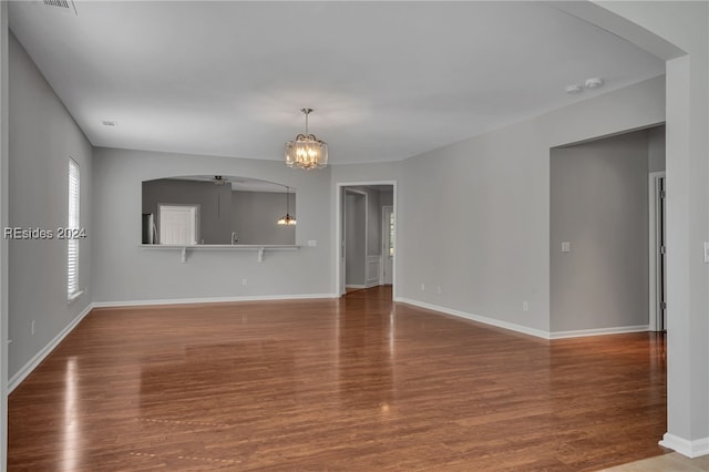 unfurnished living room featuring an inviting chandelier and hardwood / wood-style floors