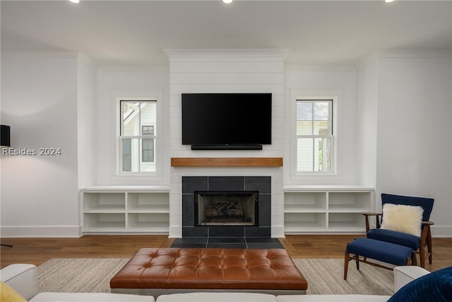 living room with hardwood / wood-style flooring, crown molding, and a tile fireplace