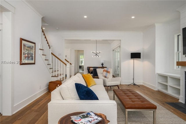 living room with dark wood-type flooring, ornamental molding, and a notable chandelier