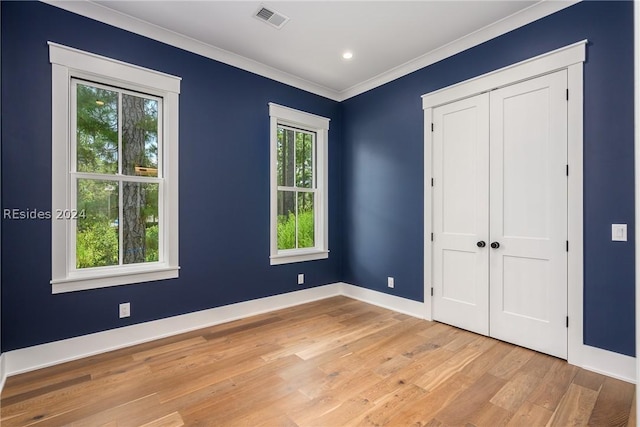 unfurnished bedroom featuring crown molding, a closet, and light hardwood / wood-style flooring