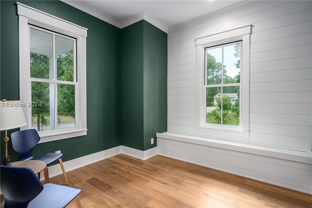 living area with crown molding and light wood-type flooring