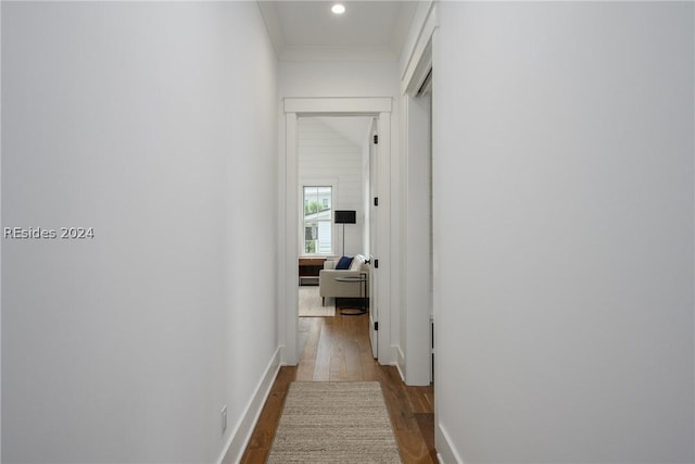 hall with ornamental molding and wood-type flooring