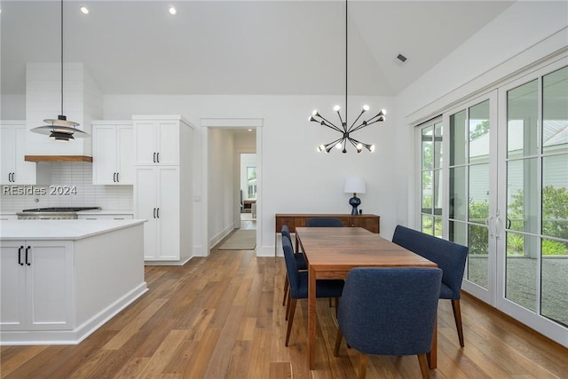 dining room featuring a notable chandelier, vaulted ceiling, and light hardwood / wood-style floors