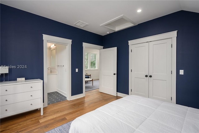 bedroom with lofted ceiling, a closet, and light wood-type flooring