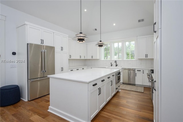 kitchen featuring white cabinetry, hardwood / wood-style floors, pendant lighting, and stainless steel appliances