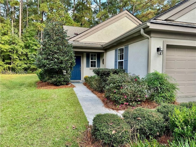 view of exterior entry with a garage and a yard