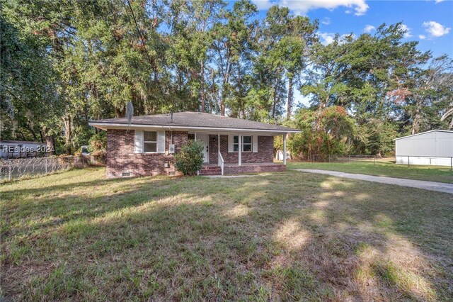 ranch-style house featuring covered porch and a front yard