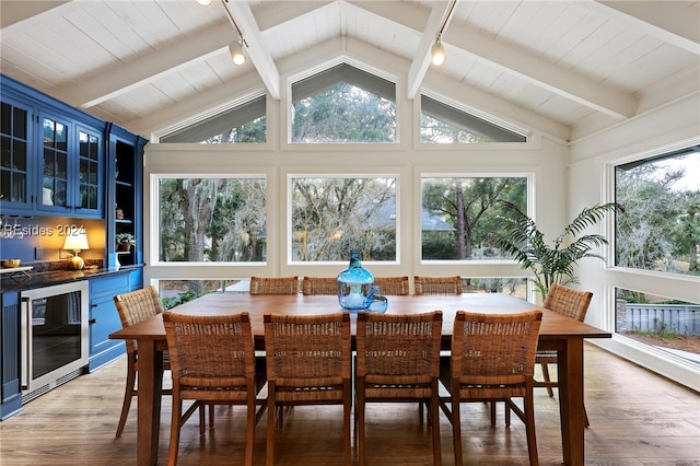 dining space with wine cooler, indoor bar, lofted ceiling with beams, and hardwood / wood-style floors