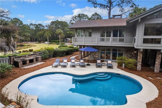 view of swimming pool featuring a patio and a fireplace